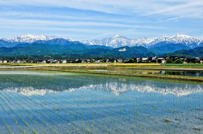 北アルプス・立山連峰と、その麓に広がる富山県上市町の風景。