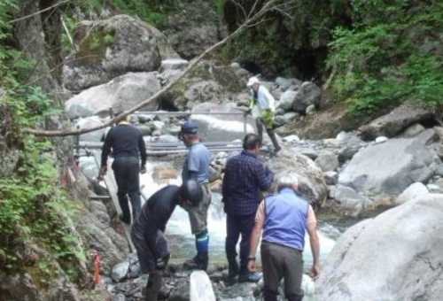 平取町山岳会が行う、鉄パイプの橋を設置する作業の様子
