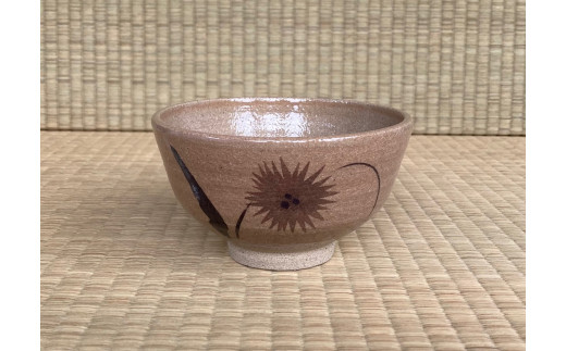 抹茶碗を正面から見た写真です。和紙染技法で表現された花と鉄絵で描かれた葉が組み合わさり独特な雰囲気を作り出しています。
