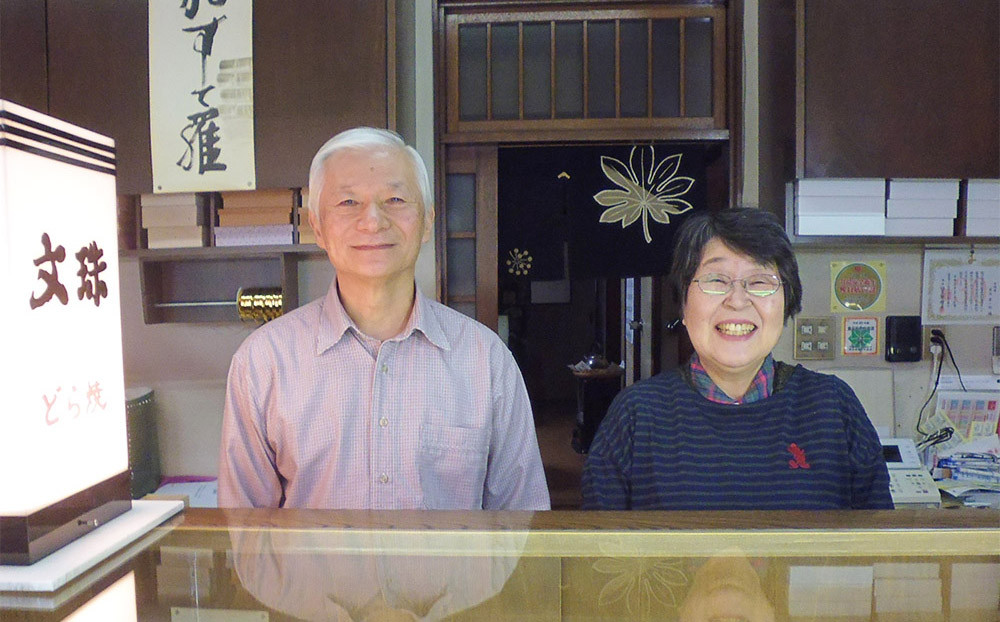 老舗呼塚屋さんの店頭で、にこやかなご夫婦の写真を撮りました。
ご主人が和菓子を作り、奥様が店頭販売と２人３脚で今日も元気です。