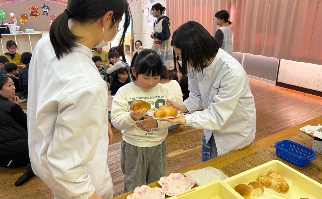 食育のイベントで子供たちにニホンミツバチの蜂蜜をふるまう高校生