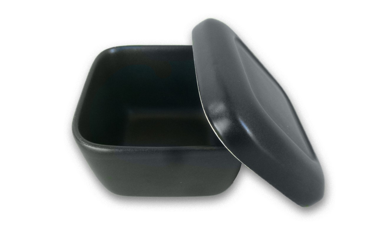 蓋が斜めに外れて半開きになっており、内部も黒く空になっている。艶のあるマットな質感で、弁当箱や保存容器のような形状。