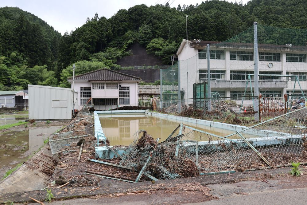 災害ゴミ置き場としている廃校となった小学校には、当日、氾濫した川の水と共に、多くの堆積物が流れてきました。
プールを囲うように設置していたフェンスは、土砂や流木などの堆積物により、なぎ倒されました。