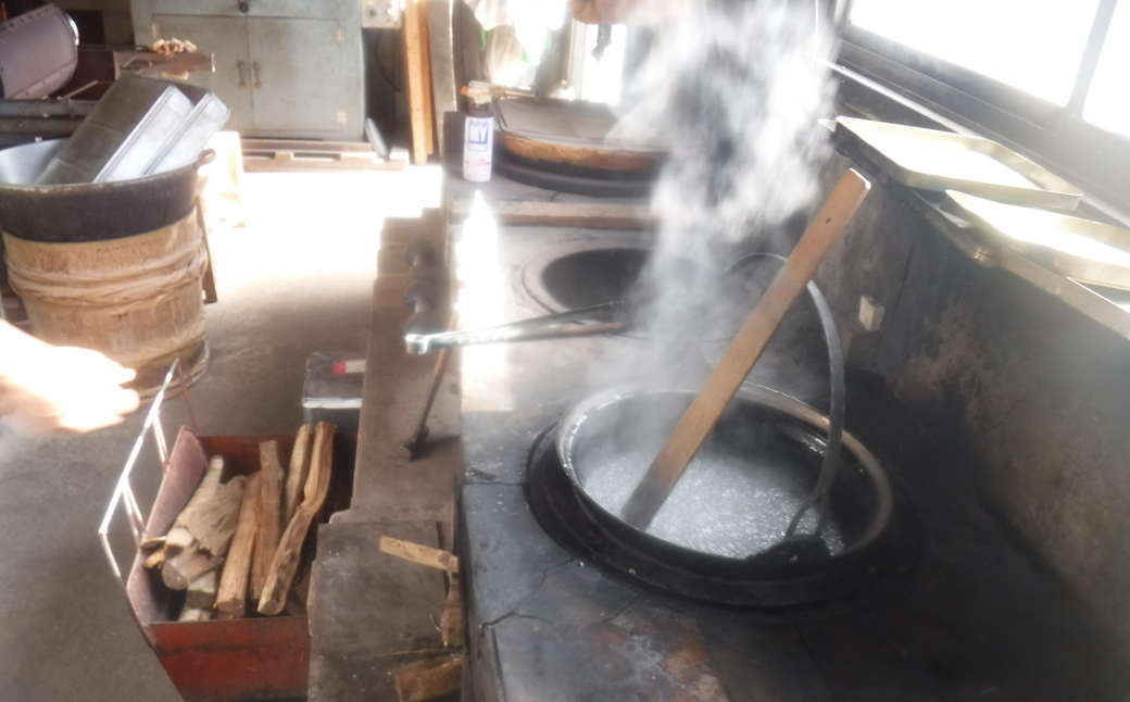 ①　薪を使って火をおこし、大きなお鍋で、飴の材料を煮詰めていきます。